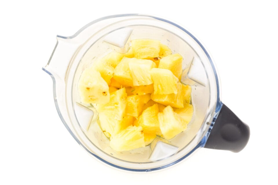 Looking down on pineapple chunks in a blender.
