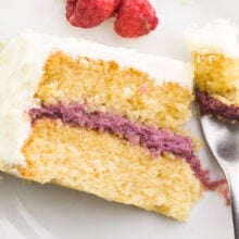 Looking down on a slice of cake on a plate. A fork has taken a bite out and is sitting next to the cake.
