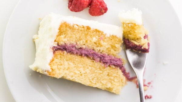 Looking down on a slice of cake on a plate. A fork has taken a bite out and is sitting next to the cake.