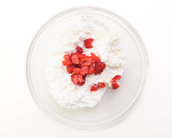 Looking down into a glass bowl full of powdered sugar and chopped raspberries.