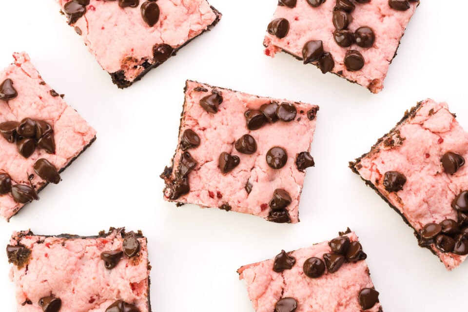 Looking down on several squares of strawberry chocolate bars, each with lots of melted chocolate chips on top.