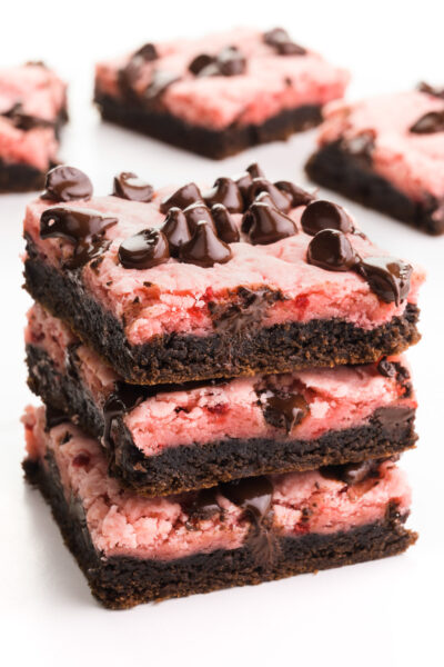 A stack of three strawberry chocolate bars sits in front of more of the bas in the background.