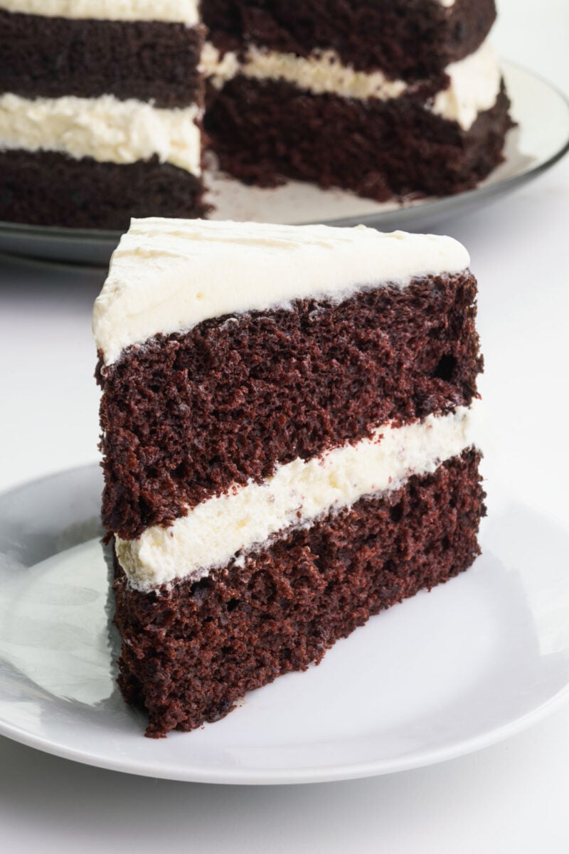 A slice of Suzy Q Cake sits on a plate in front of the rest of the cake.