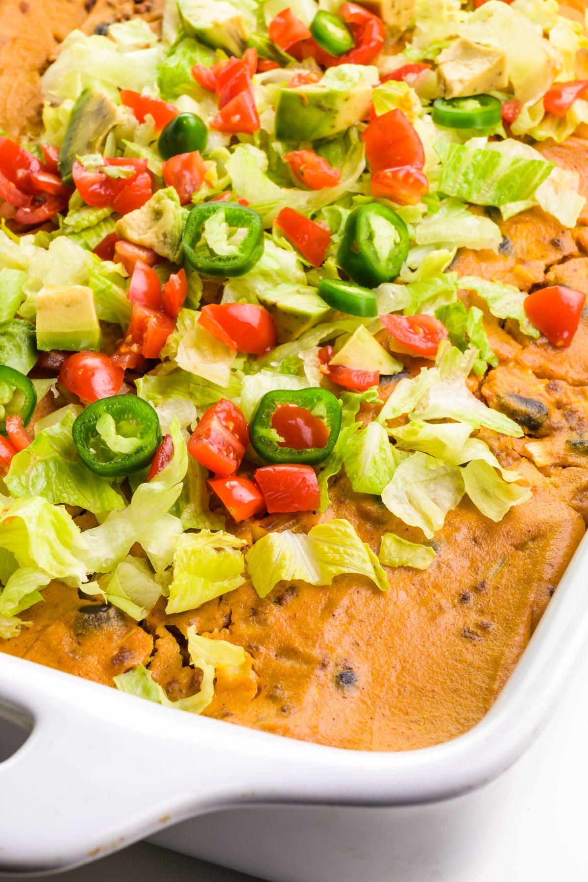 Looking down on a vegan tortilla casserole with lots of colorful chopped veggies on top.