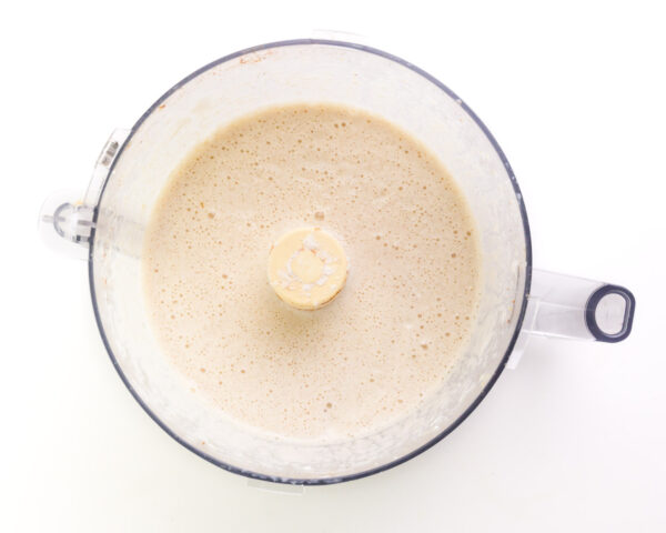 Looking down on a soy milk mixture in a food processor bowl.