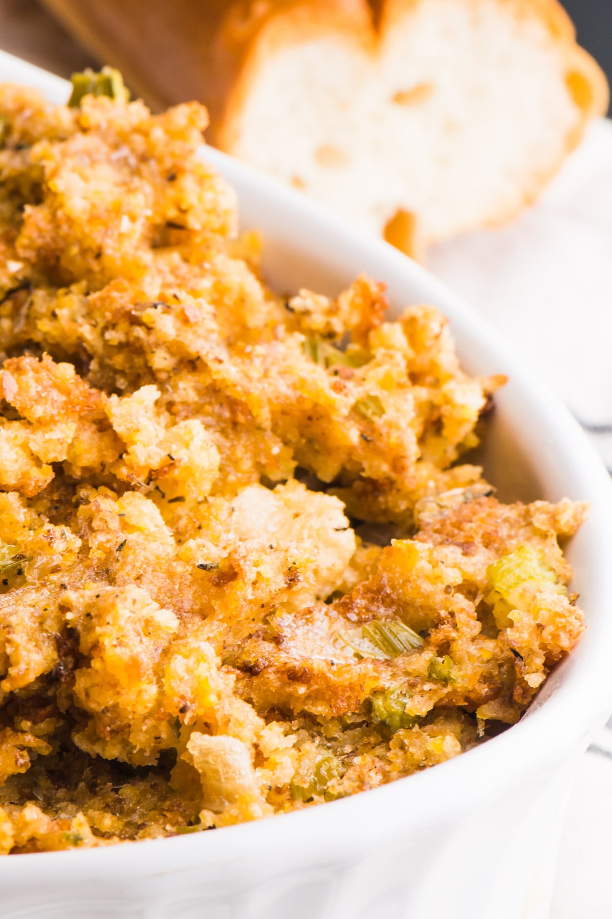 Vegan stuffing is in a white baking dish. There's a loaf of bread in the background.