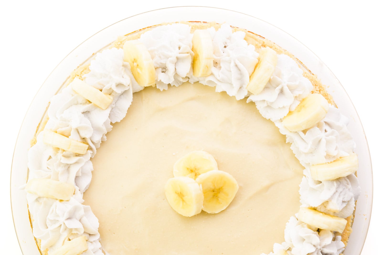 Looking down on a banana cream pie with whipped cream fluted around the edges and slices of fresh banana on top.