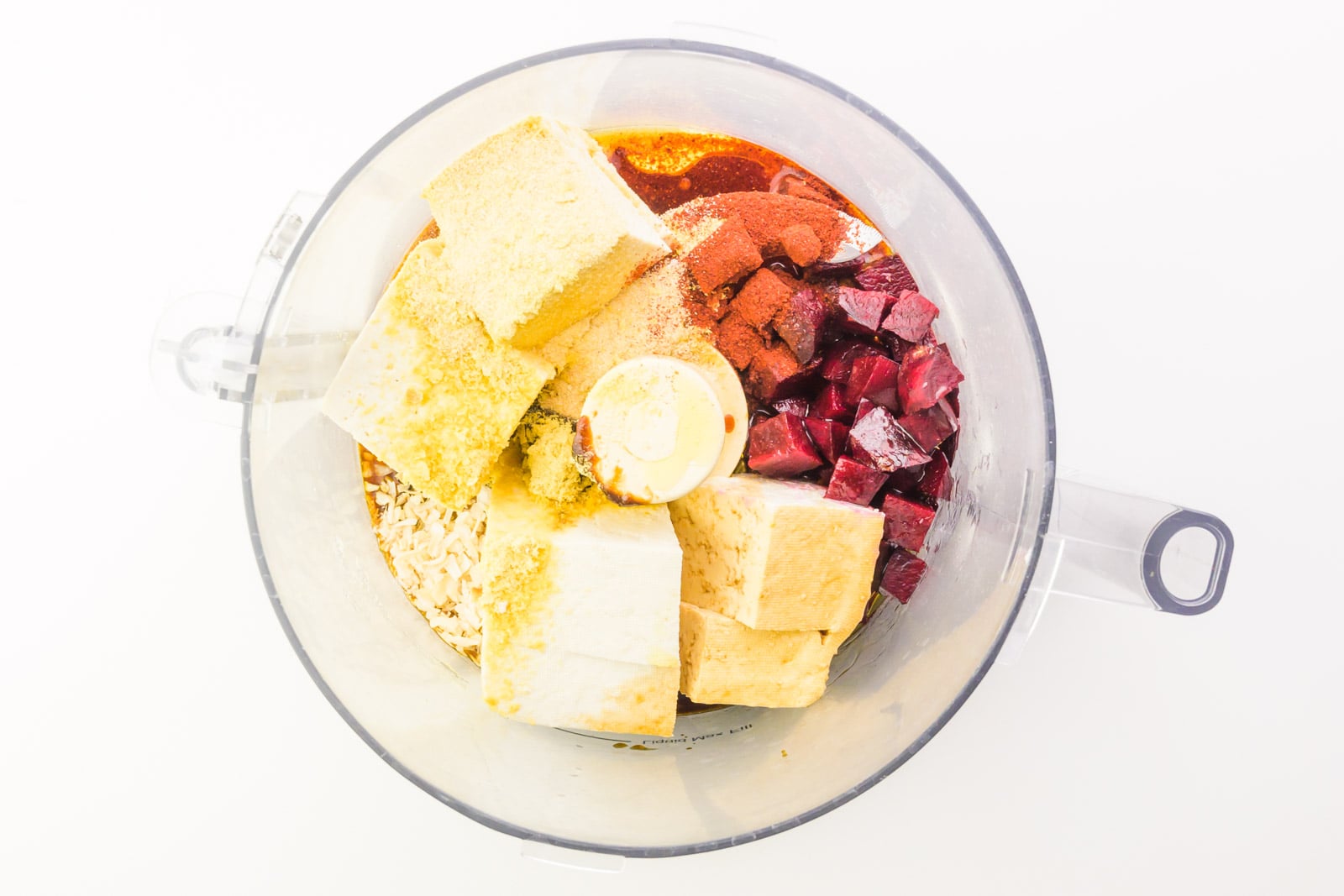 Ingredients, including beets, are in the bottom of a food processor.