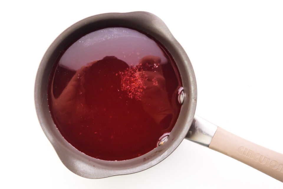 A red mixture is in the bottom of a saucepan.