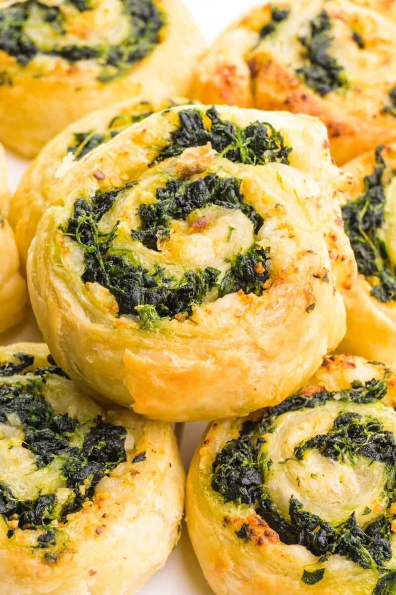 A spinach pinwheel sits on top several other pinwheels.