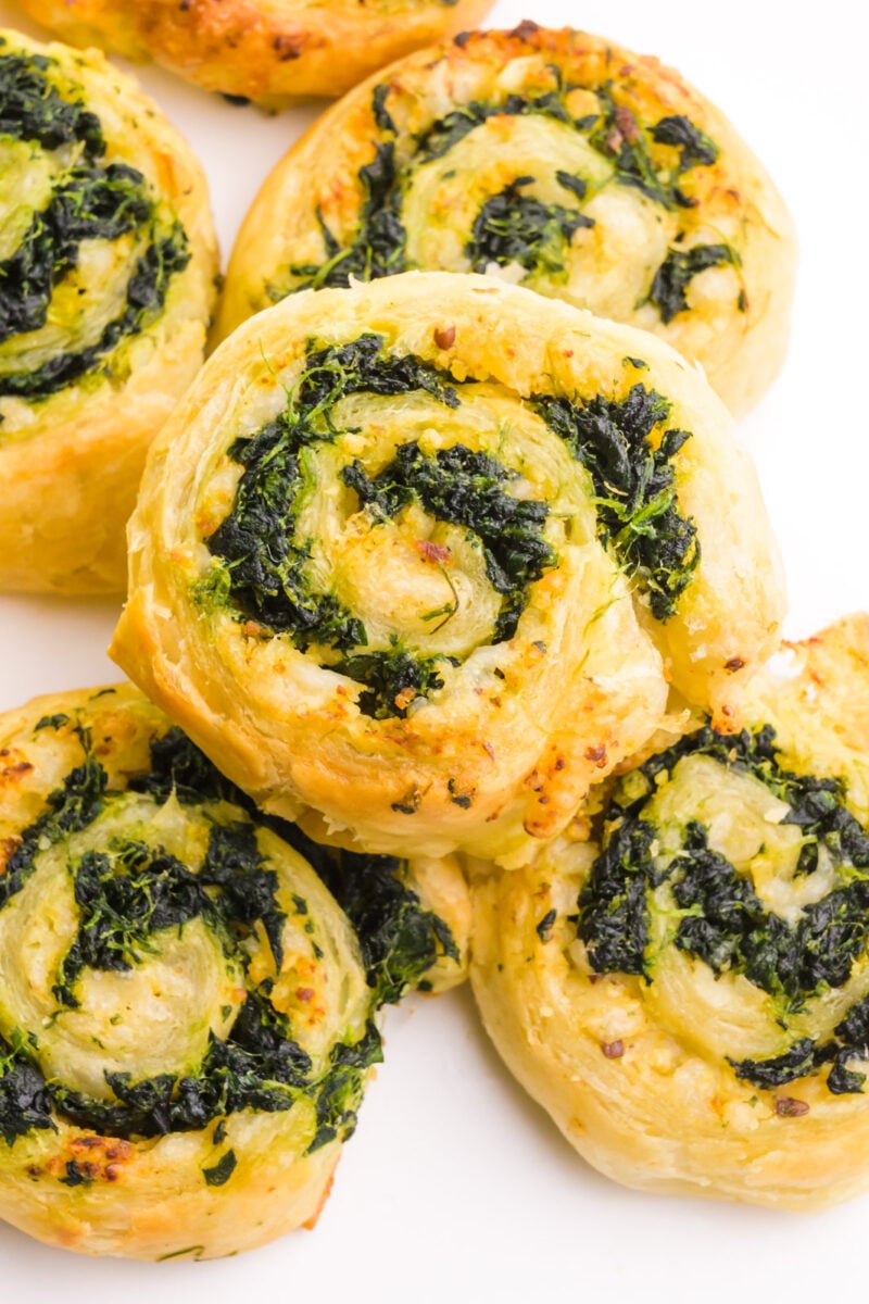 Looking down on several vegan spinach pinwheels, one stacked on the top.