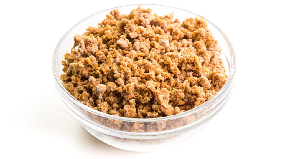 Veggie crumbles sit in a glass bowl on a white counter.