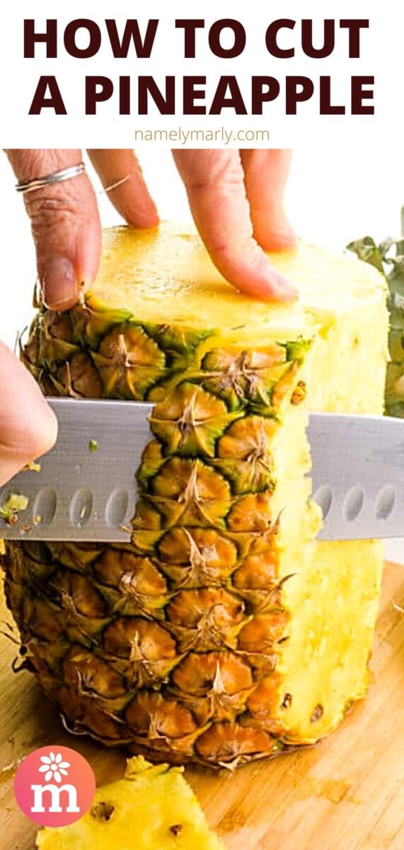 A fresh pineapple has both ends cut off and is sitting tall on a cutting board. A hand holds it steady on top while a knife cuts off part of the skin. The text at the top reads, How to Cut A Pineapple.