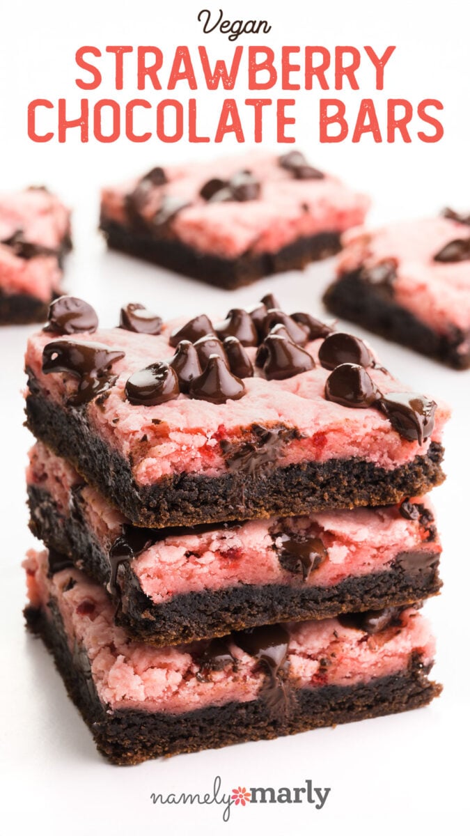 Vegan strawberry chocolate bars stacked with chocolate chips on top, set against a light background.