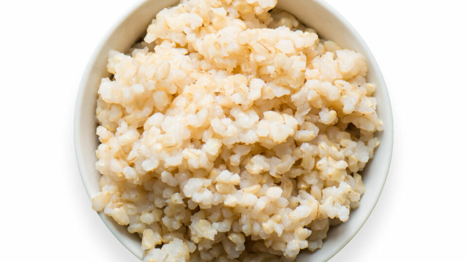 A small, white bowl is full of cooked rice.