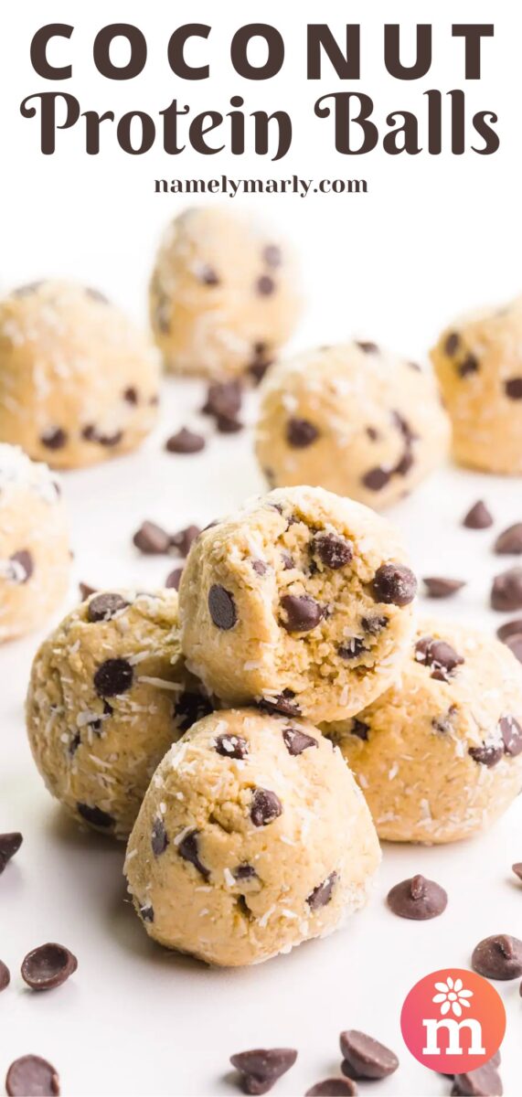 A mound of protein balls shows the top one with a bite taken out, revealing lots of chocolate chips inside. There are more coconut balls in the background with chocolate chips on the table around them. The text at the top of the image reads, Coconut Protein Balls.