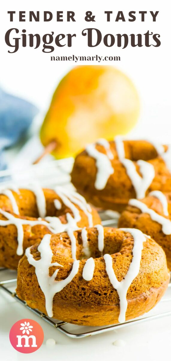 Donuts with frosting drizzled on top sit on a wire rack. There's a golden pear in then background sitting next to a blue kitchen towel. The text at the top of the image reads, Tender & Tasty Ginger Donuts.