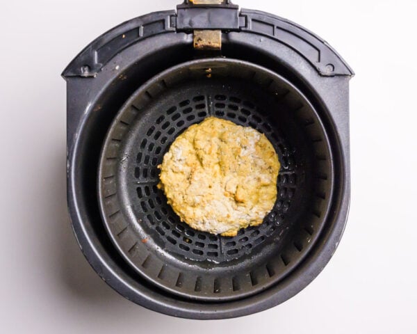 A fried tofu patty is in an air fryer basket.