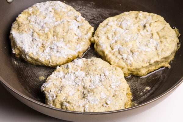 Breaded tofu patties are frying in a skillet.