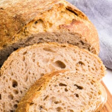 A loaf of whole wheat bread has slices sitting in front of it.