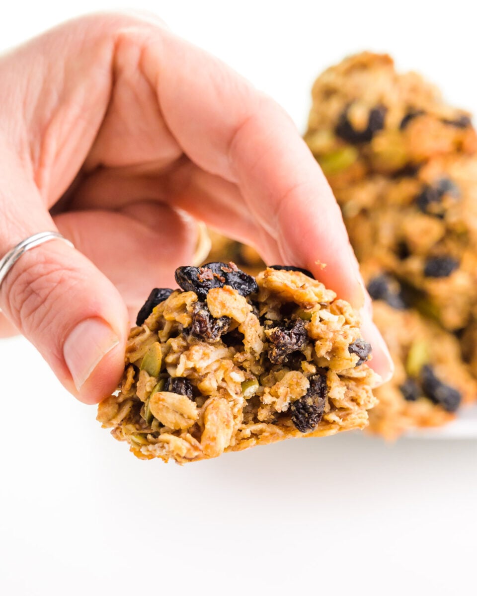 A hand holds a vegan breakfast cookie with a bite taken out.