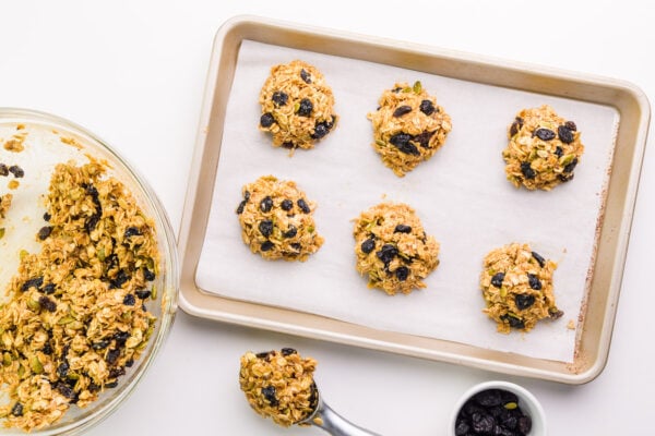 Looking down on a baking tray with cookie dough balls. It sits next to a bowl with more cookie dough batter.