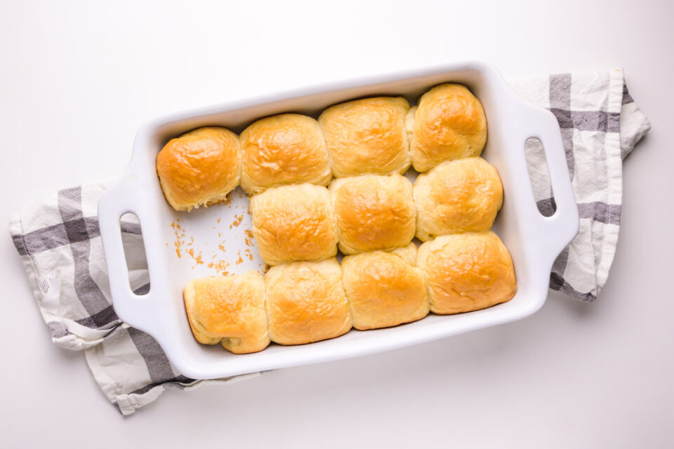 Looking down on a baking dish full of vegan bread rolls, with one missing.