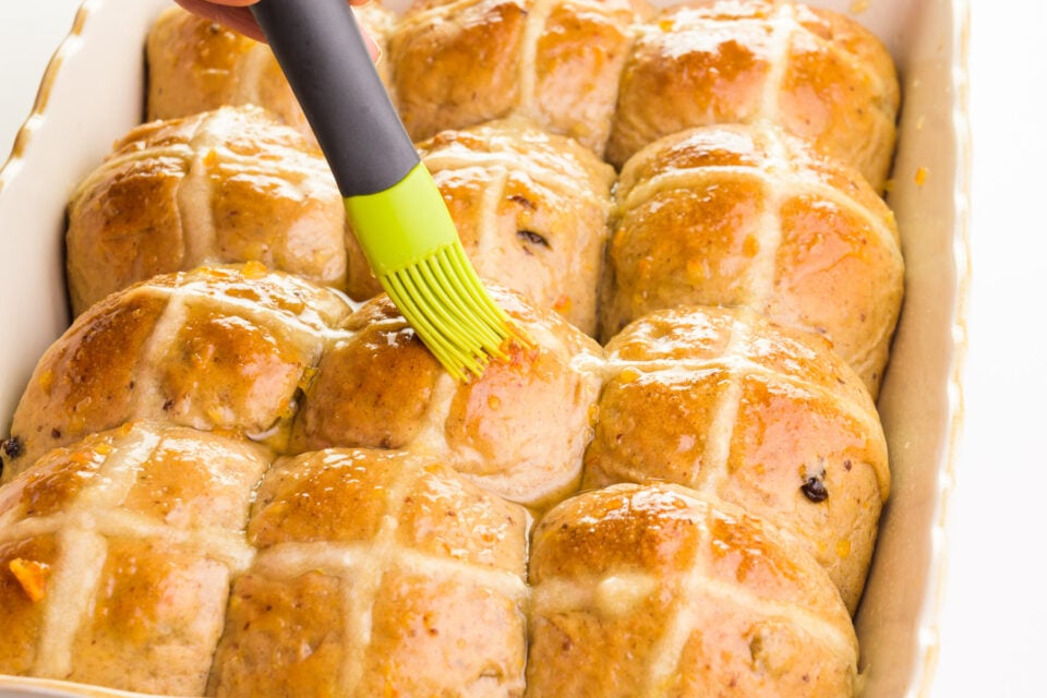 Baked rolls are being brushed with a shiny glaze.