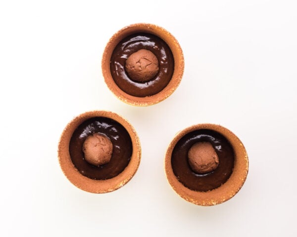 Looking down on three ramekins with batter and chocolate balls in each.