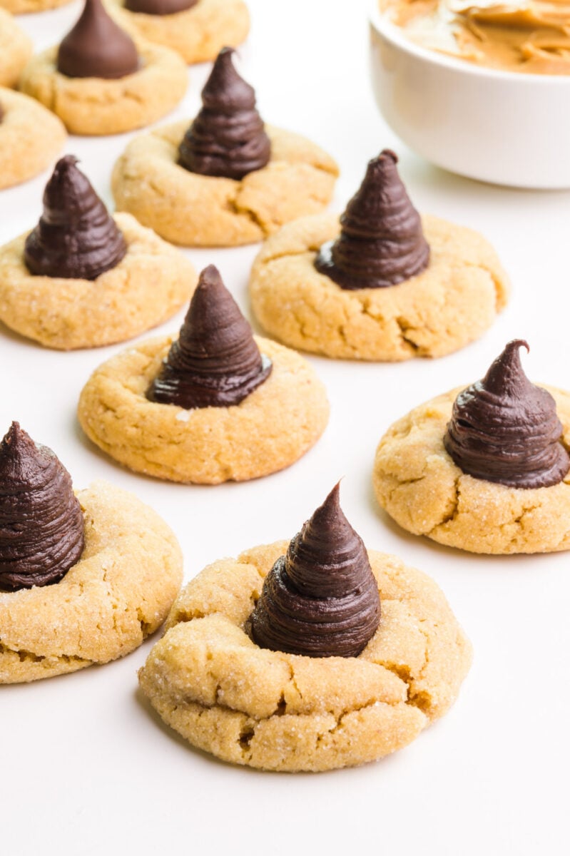 Vegan peanut blossoms with chocolate ganache centers sit next to each other on a white counter.