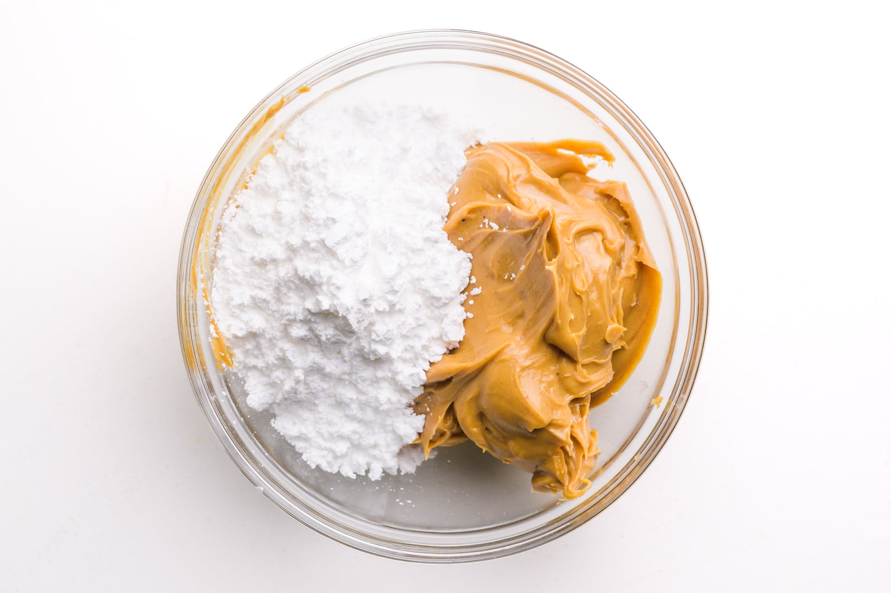 Powdered sugar and peanut butter are side by side in a bowl together.