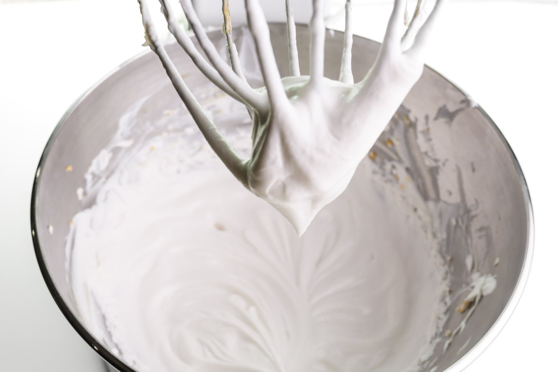 Coconut milk has been whipped using a stand mixer. The beats and the bowl are shown.
