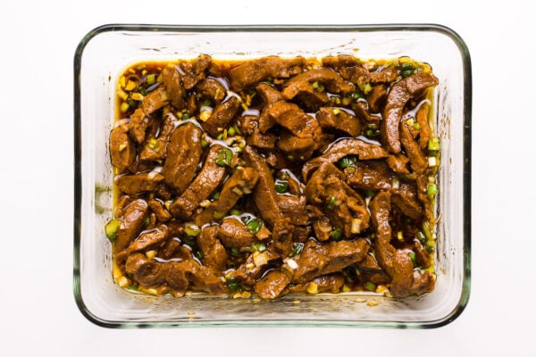 Seitan sits in a marinade in a glass baking dish.