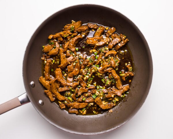 Seitan is in a skillet being cooked with a sauce.