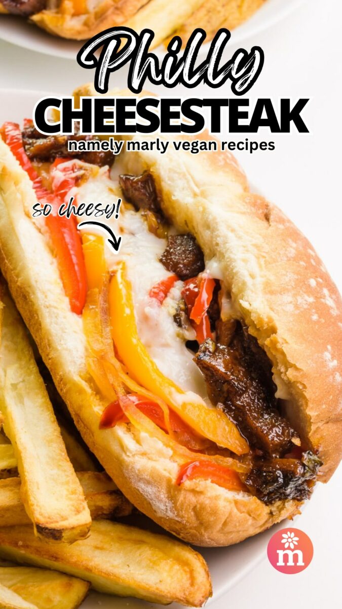 A sandwich on a hoagie bun sits on a plate next to fries. The text reads, Philly Cheesesteak, Namely Marly Vegan Recipes. An arrow points to the sandwich and has text that reads, So Cheesy!