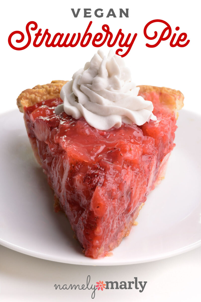 A slice of vegan strawberry pie topped with whipped cream on a white plate.