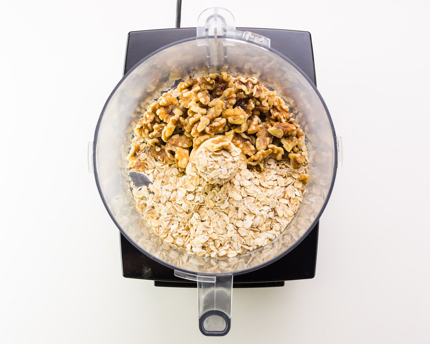 Walnuts and oats are in a food processor.