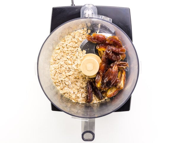 Oats and dates are in a food processor.
