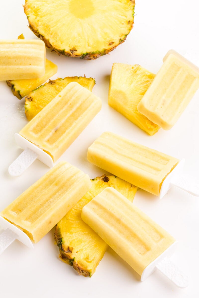 Looking down on popsicles sitting next to fresh pineapple.