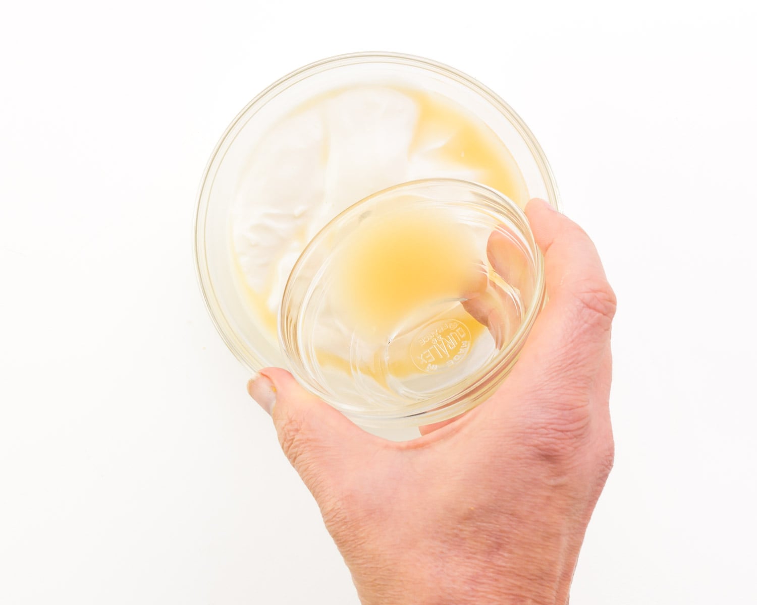 Lemon juice is being poured into a bowl with vegan mayo.
