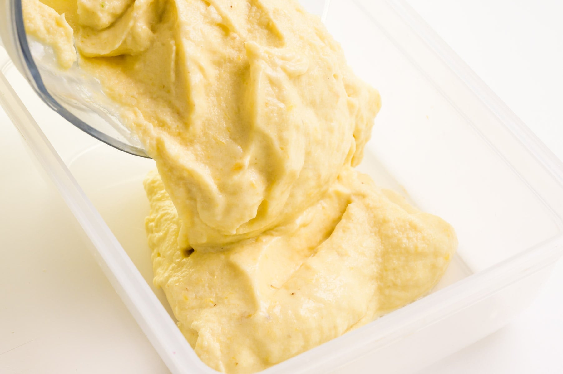 dairy-free frozen yogurt is being poured from a blender into a container for freezing.
