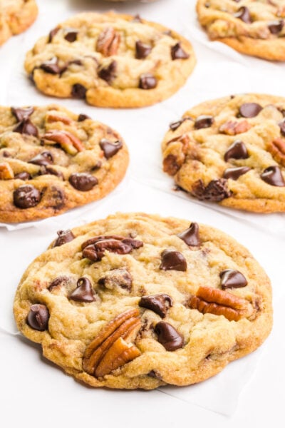 Chocolate chip pecan cookies are laid out on a white table.
