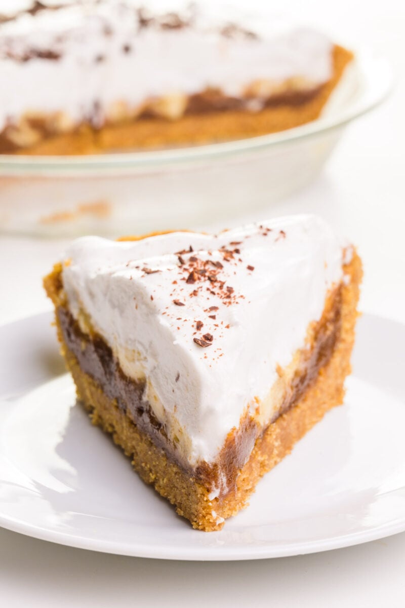 A slice of healthy banoffee pie sits on a plate in front of the rest of the pie in the background.