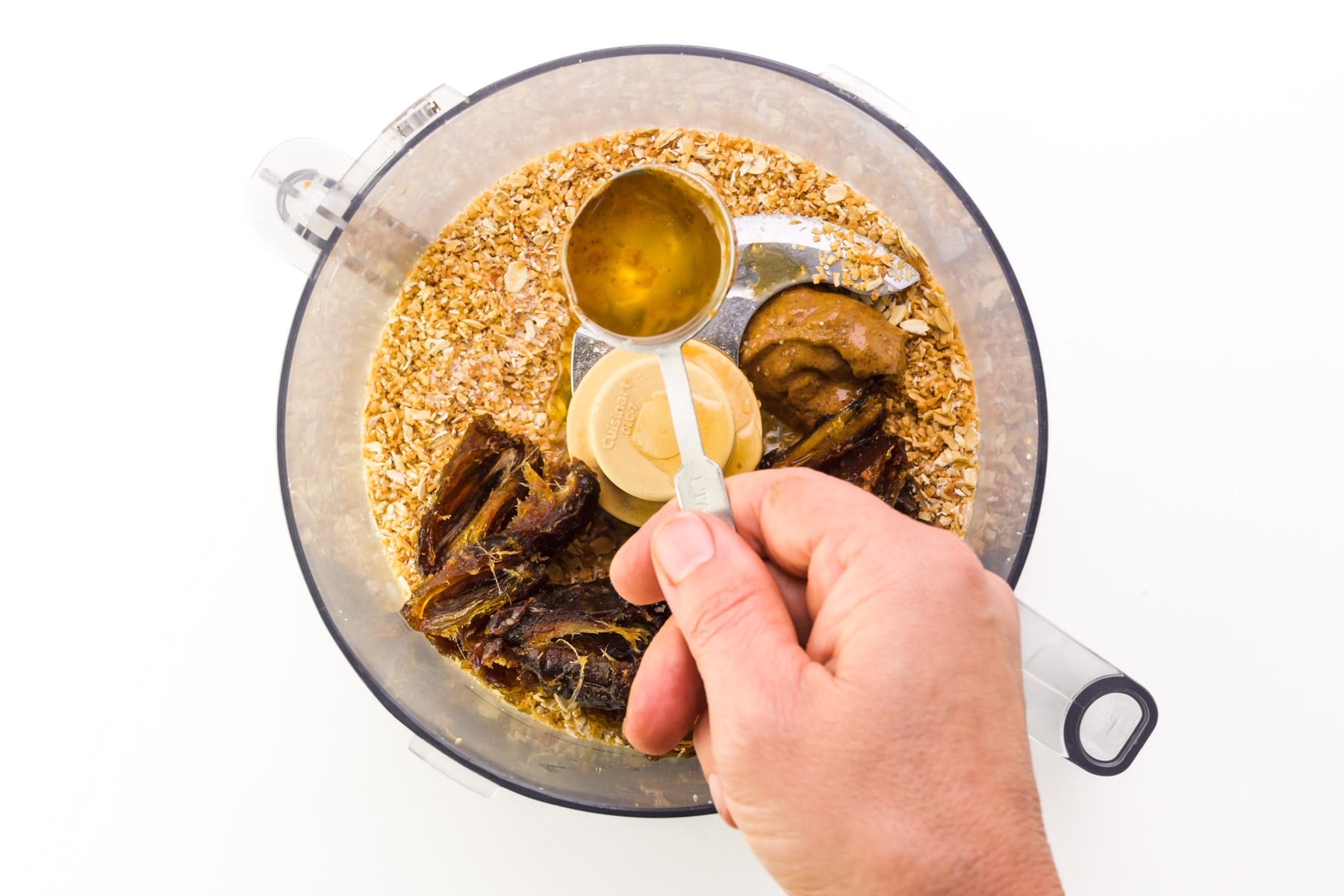 Maple syrup is being added to a food processor.