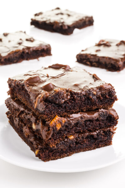 A stack of three slices of vegan sheet cake sits on a plate. There are more slices in the background.