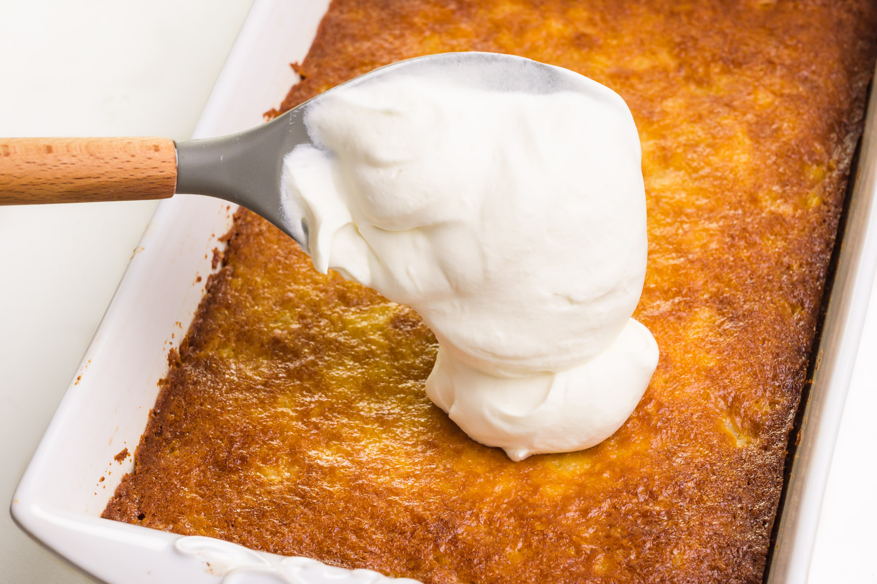 Whipped cream is being spooned onto a cake.