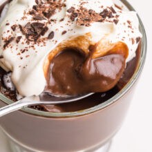Looking down into a spoon in a bowl of vegan pudding with whipped cream on top.
