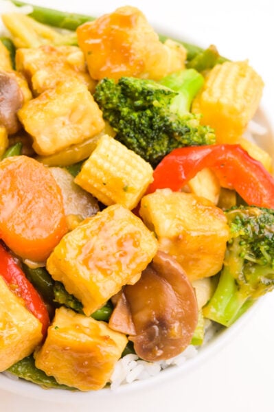 A bowl of teriyaki tofu stir fry features veggies and fried tofu with a thick sauce.
