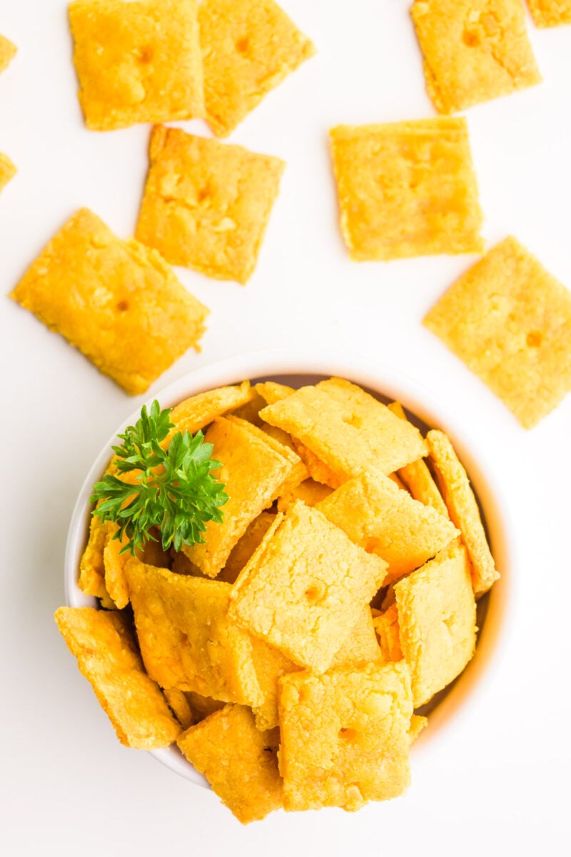 Looking down on a bowl of vegan cheese crackers. There are more crackers behind the bowl.