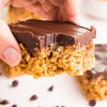 A hand holds a vegan scotcharoo bar with a bite taken out.